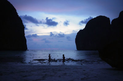 Silhouette people on beach against sky during sunset