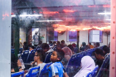 People on illuminated street seen through glass window