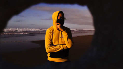 Young boy standing on beach against sky