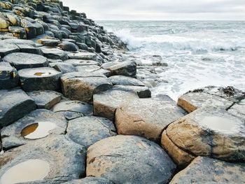 Stone wall by sea against sky