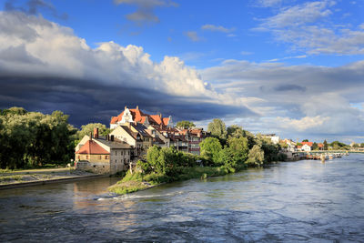 Buildings by river against sky