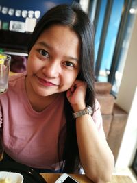 Close-up portrait of smiling woman sitting in restaurant