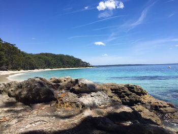 Scenic view of rocks on beach against blue sky