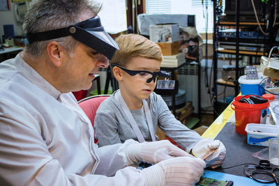 Worker teaching boy in workshop