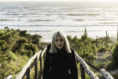 Portrait of young woman standing by sea