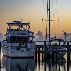 Boats moored in harbor at sunset