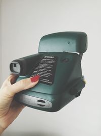 Close-up of hand holding camera over white background