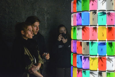 Young man standing against multi colored wall