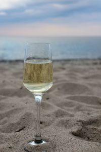 Wine glass on beach against sky