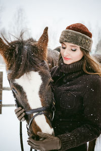 Close-up of beautiful woman with horse on field during snowfall