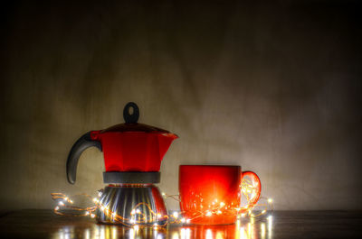 Close-up of illuminated lantern on table against wall
