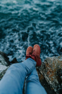 Low section of person on rock over sea