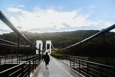 Rear view of man walking on footbridge