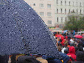 Close-up of wet umbrella with people in background