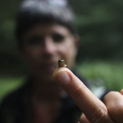 Close-up of small frog on finger