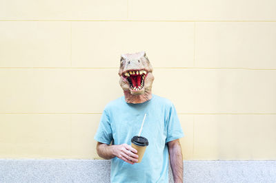 Midsection of man holding ice cream standing against wall