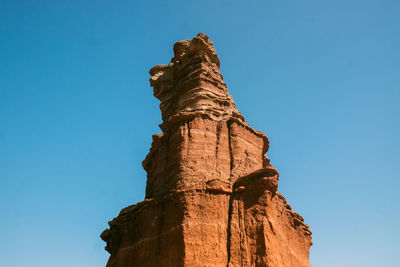 Low angle view of rock formation against clear blue sky