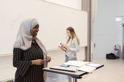 Smiling woman rehearsing presentation with friend at lecture hall in university