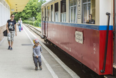 Happy son with mother walking on railroad station platform