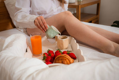 Midsection of woman holding food while sitting on bed