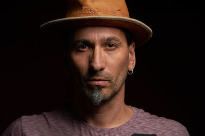 Portrait of man wearing hat against black background