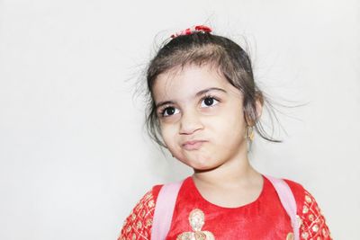 Cute girl looking away while standing against white background