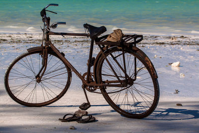 Flip-flops and rusty bicycle on sea shore