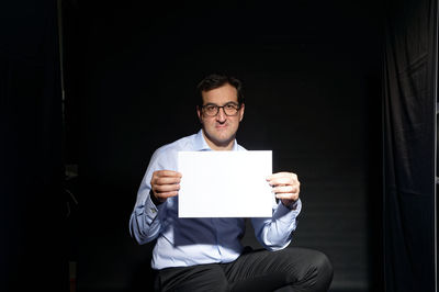 Portrait of young man holding eyeglasses
