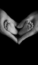 Close-up of baby hands against black background