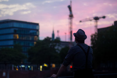 Rear view of man standing against sky during sunset