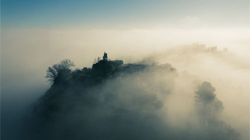 Aerial view of the medieval village of fiorenzuola di focara immersed in fog near pesaro e urbino