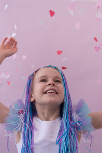 Portrait of young woman with arms raised