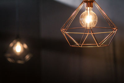 Low angle view of illuminated light bulb hanging on ceiling