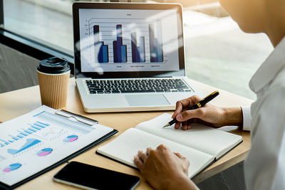 Midsection of man using laptop on table