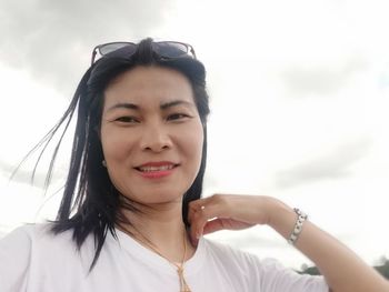 Portrait of smiling young woman against sky