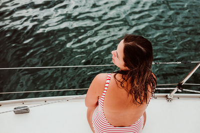 Rear view of woman standing by railing in water