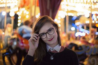 Close-up portrait of smiling young woman wearing eyeglasses at night