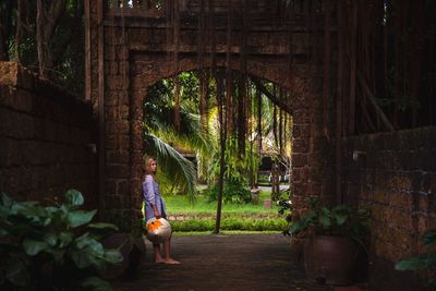 Portrait of teenage girl leaning against built structure 