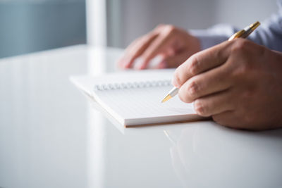 Midsection of woman reading book on table