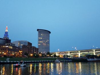 River by illuminated buildings against clear sky