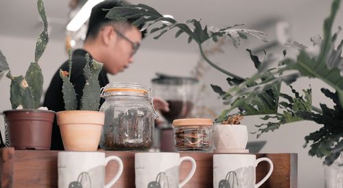 Close-up of woman looking at potted plants on table