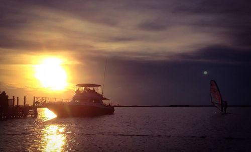 Silhouette ship sailing on sea against sky during sunset