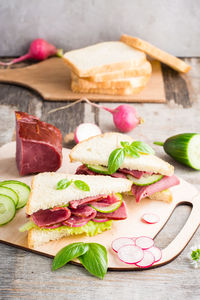 Fresh sandwiches with pastrami and vegetables on a cutting board. american snack