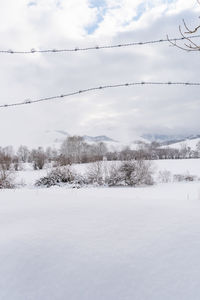 Scenic view of snow covered field against sky