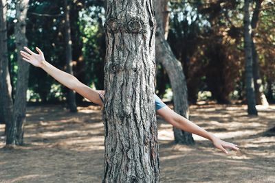 Low angle view of young woman against tree trunk