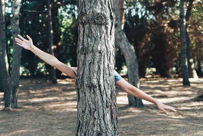 Low angle view of young woman against tree trunk