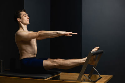 Shirtless man exercising against black background