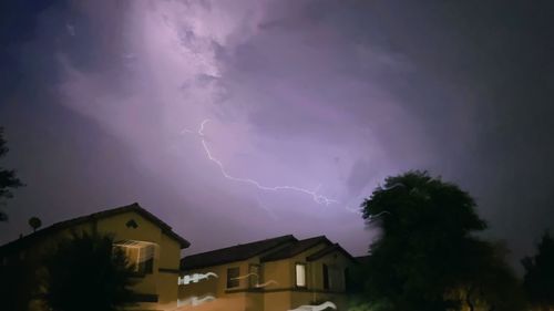 Low angle view of lightning over buildings against sky