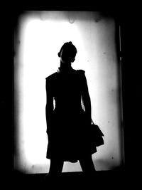 Rear view of silhouette woman standing against wall