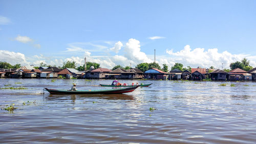 Man sitting in boat on lake against sky